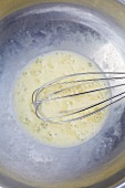 Beaten Eggs in a Bowl with a Whisk