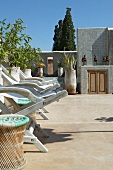 Deckchairs and potted plants on sunny, Mediterranean roof terrace