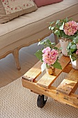 Flowering potted plants on table made from pallet on castors