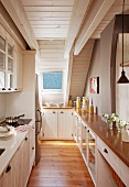Narrow attic kitchen - country-style kitchen counter and half-height fitted cupboards