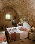Double bed with headboard against stone wall in bedroom with barrel vault ceiling