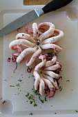 Cooked, skinned octopus with a knife on a chopping board
