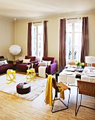 Set dining table next to lounge area with yellow side tables and purple sofa set in front of French windows with floor-length curtains
