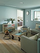 Rustic coffee table on castors in lounge area with walls painted pale blue and view through open bedroom door