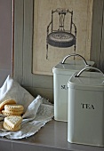 Vintage storage cans with labels next to biscuits on cloth