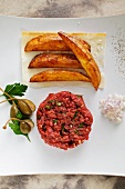 Beef tatar with potato wedges and capers