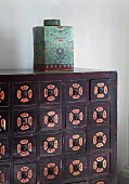 Oriental porcelain jar with lid on wooden chest of drawers painted with patterns