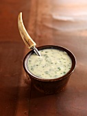 A bowl of parsley sauce with a horn-handle spoon