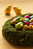 Coloured chocolate Easter eggs in a moss wreath