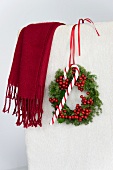 Christmas wreath of holly berries and conifer hanging on chair back with candy cane