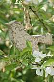 Vogelfigur aus Holz auf Zweig