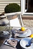 Crackers next to stack of plates and lantern on garden table in front of rustic house