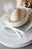 Breakfast place setting with egg, decorative feather and ceramic spoons