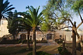 Mediterranean garden with palm trees in front of manorial residential complex