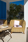 Comfortable wicker armchair and side table on Mediterranean veranda