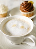 Eine Tasse Milchkaffee mit Cup-Cakes