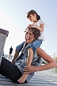 Mother and daughter sitting on pier