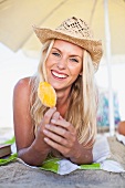 Smiling woman eating popsicle on beach