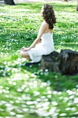 Young woman sitting in lotus position in meadow, side view, selective focus