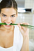 Woman biting into chives, smiling