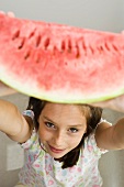 Mädchen hebt eine Wassermelonenspalte hoch