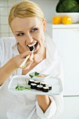 Young woman eating sushi