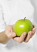 Woman's hand holding out apple