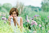 Young woman in garden, eating piece of watermelon