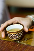 Hand reaching for colorful tea cup full of tea