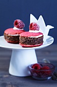 Mini cakes on a cake stand with sugared raspberries