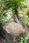 Kompostbehälter aus Maschendrahtgitter mit Gartenabfällen