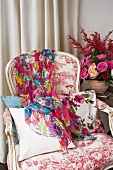 Buntes Tuch auf Sessel im Rokokostil neben Blumengesteck