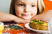 A little girl looking at a slice of spicy French toast