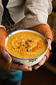 A woman holding a ball of butternut squash and coconut soup