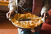 A person serving goat's cheese and spinach pie