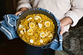 A cook holding a bowl of kedgeree