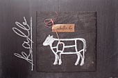 A sketch of a calf and a written label on a chalkboard