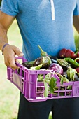 A man carrying a crate of aubergines