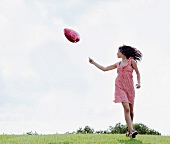 Teenager holding heart-shaped balloon in meadow