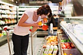 A woman smelling fruit in a supermarket
