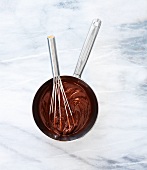 Melted chocolate in a pot with a whisk (seen from above)