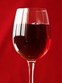 Ein Glas Rotwein vor rotem Hintergrund