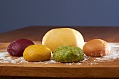 Various different coloured pasta doughs on a work surface