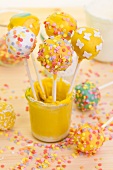 Various cake pops in a glass of yellow icing