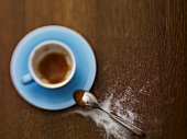 An almost-empty espresso cup and sugar sprinkled next to it