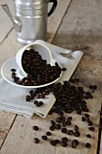 Kaffeebohnen fallen aus umgekippter Espressotasse