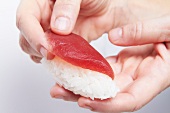 Hände halten Nigiri-Sushi mit Thunfisch