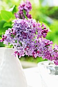 Purple lilac in vase on garden table