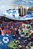 Table cloth decorated with plastic flowers and chocolate bowl with chocolate spoon on plate