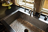 Metal sink with vintage tap fittings in front of window